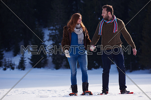 happy young  couple having fun and walking in snow shoes. Romantic winter relaxation scene