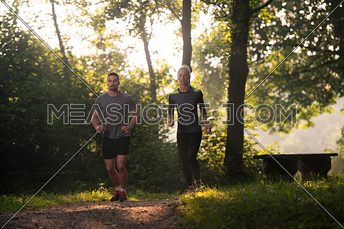 Young Couple Running In Wooded Forest Area - Training And Exercising For Trail Run Marathon Endurance - Fitness Healthy Lifestyle Concept