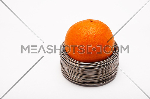 Wired orange: whole orange in coils of aluminium wire isolated on white background