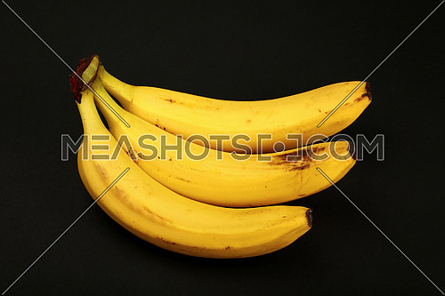 One fresh ripe yellow banana isolated on black paper background, close up, high angle view