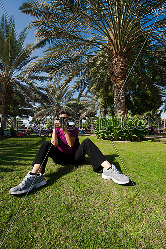 A woman sitting on the grass holding a camera in a park