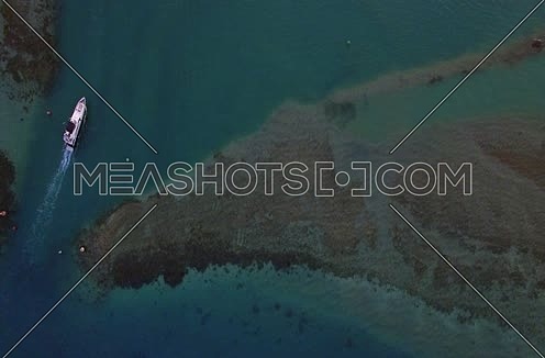 Drone shot flying above the red sea and a yacht moving at Day 