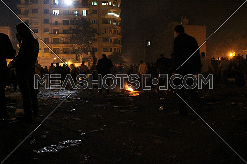 a wide shot for tahrir square at night during revolution and fire on the ground