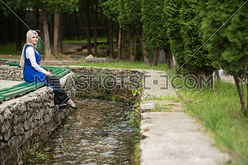 Portrait Of Young Muslim Woman Sitting On A Bench Next To The River