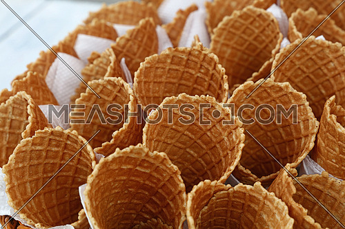 Several empty fresh wafer ice cream cone cornet cups with white paper napkins, close up, elevated high angle view