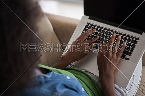 Young african american woman at home in the chair relaxing in her luxury lliving room reading  laptop PC surf internet and work