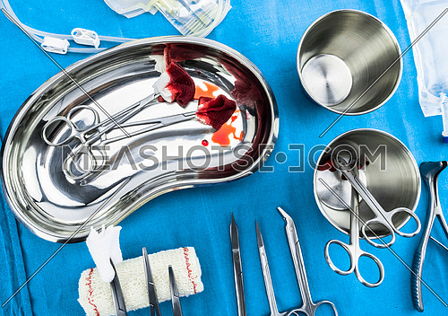Scissors surgical with torundas soaked with blood on a tray metal in an operating theater, composition horizontal, conceptual image