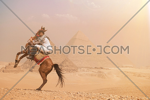 young Egyptian man horse rearing in desert giza platue with the pyramids in background