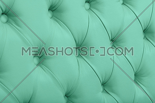 Close up background texture of pastel teal green capitone genuine leather, retro Chesterfield style soft tufted furniture upholstery with deep diamond pattern and buttons