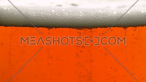 Close up background of cola with bubbles or dark lager beer in glass, low angle side view, slow motion