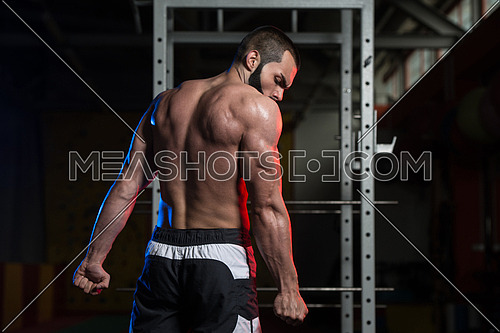 Portrait Of A Young Fit Man Showing Side Triceps Pose - Muscular Athletic Bodybuilder Fitness Model Posing After Exercises