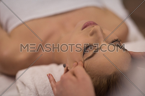 Young beautiful relaxed woman receiving a head massage in a spa centre