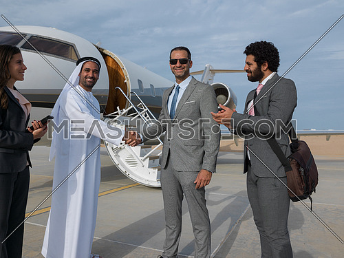 Young successful businessmen shake hands with their Arab business partner in front of the private airplane
