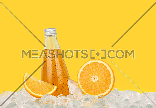 Close up one glass bottle of cold orange juice cocktail drink with chia seeds and half cut orange on ice cubes isolated on yellow background, low angle side view