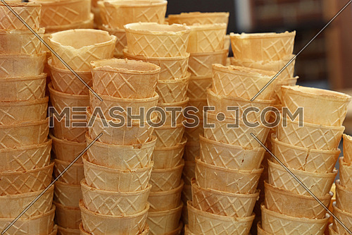 Background of empty fresh wafer ice cream cone cornet cups in row stacks, close up, low angle side view