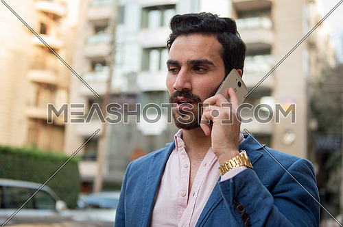 A young man is talking on a mobile phone in the street
