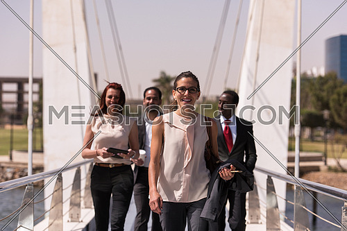 young multi ethnic business people group walking across modern bridge and drink first morning coffee