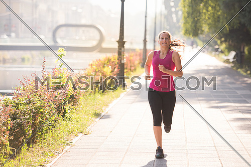 young sporty woman jogging at sunny morning in the city