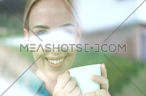 Blond looking thorugh window and drinking coffee