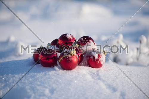 christmas red balls with long shadows  in fresh snow on beautiful sunny winter day