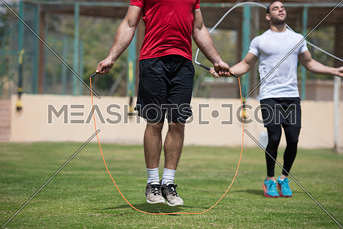 Young middle eastern athletic guys exercise skipping rope outdoors