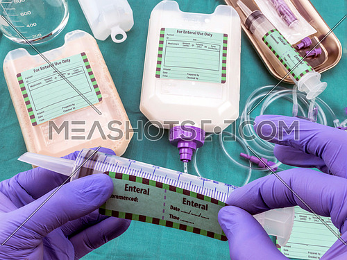 Nurse placed label on syringe of enteral nutrition, palliative care in hospital, conceptual image, composition hotizontal