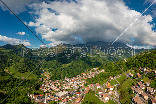 Drone aerial view to the Seriana valley and Orobie Alps with big cloud and blue sky