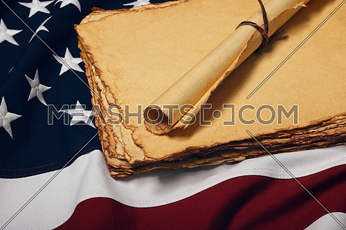 Close up blank old vintage yellow paper sheets and scroll on cotton embroidered US national flag background, symbol of American history, elevated high angle view