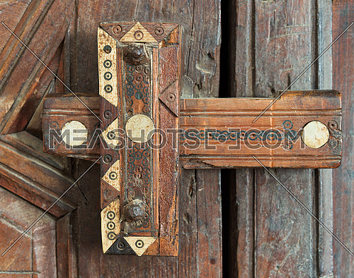 Closeup of a wooden aged ornate latch over a wooden door