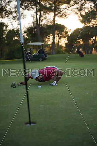 golf player blowing ball in hole. concept of cheating and success, beautiful sunset in backgrund