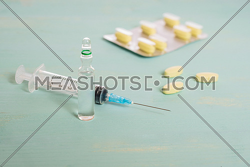 Medical vials,tablets and syringe isolated on green background, vaccination concept and disease treatments