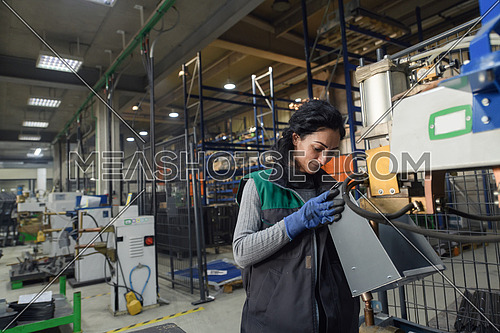 a woman working in a modern metal factory assembles parts for a new machine. High quality photo