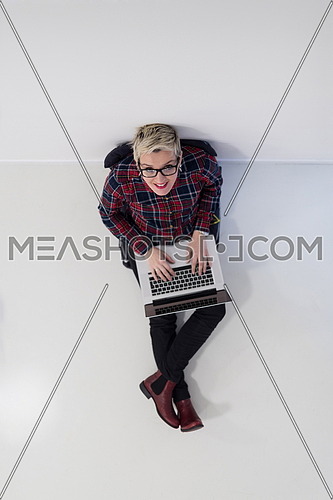 top view of young business woman working on laptop computer in modern bright startup office interior, sitting on floor