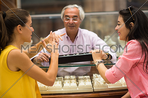 two young happy middle eastern women enjoy trying out jewelry in a luxury jewelry store