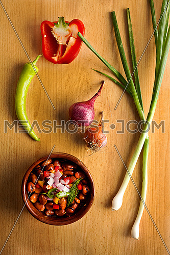 this is a shot for Egyptian beans (foul) plate on a wooden table with onions and pepper... egyptian breakfast