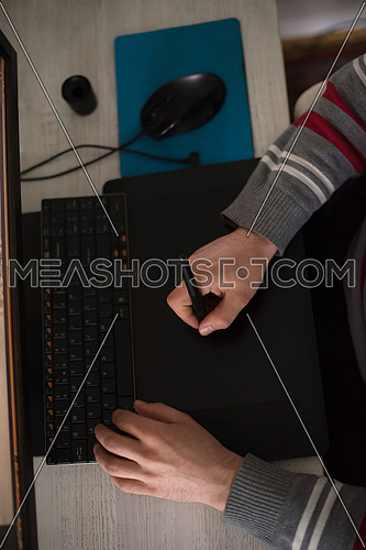 Young graphic designer working on a digital tablet and a computer top view