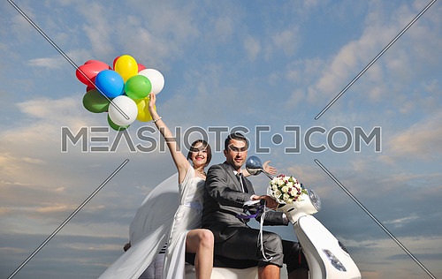 wedding sce of bride and groom just married couple on the beach ride white scooter and have fun