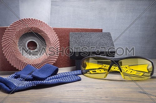 Various grinding tools - sanding belt, abrasive sponge and flap disc for angle grinder, safety gloves and goggles, renovation, safety and health at work concept