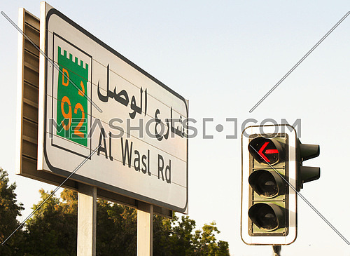 Al Wasl street sign in Dubai with a red traffic signal