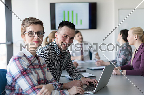 young startup  business people, couple working on laptop computer,  businesspeople group on meeting in background at office interior