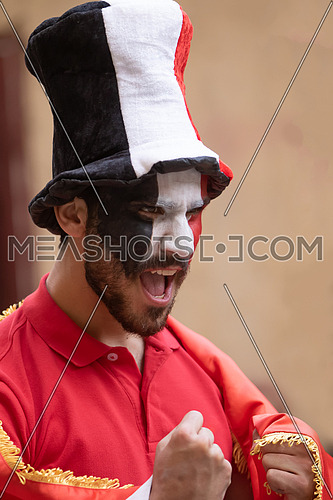 A male Egyptian fan painting a flag on his face wearing supporter's hat