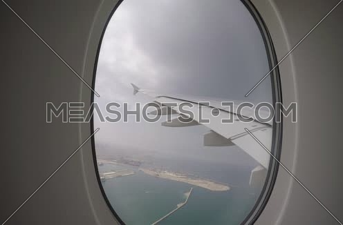 shot from plane window showing wing flying over Dubai city at day