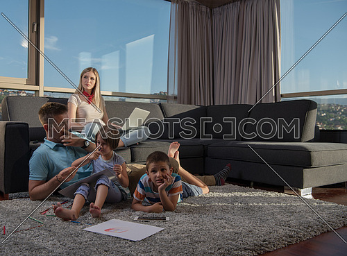 Happy Young Family Playing Together at home on the floor using a laptop computer and a children's drawing set