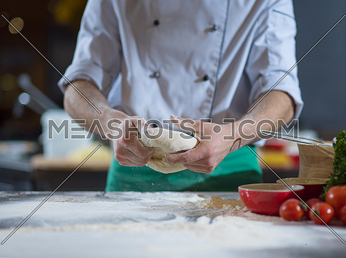 chef hands preparing dough for pizza on table sprinkled with flour closeup