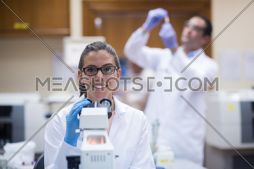 portrait of a young middle eastern woman with a microscope in a large modern laboratories