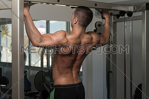 Young Male Athlete Doing Pull Ups - Chin-Ups In The Gym