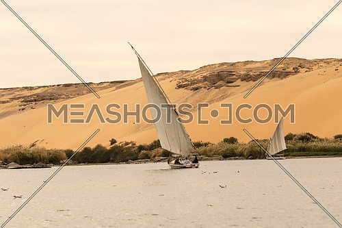 Ferry boat in River Nile, Aswan, Egypt. And sand hill in the background and some bushes