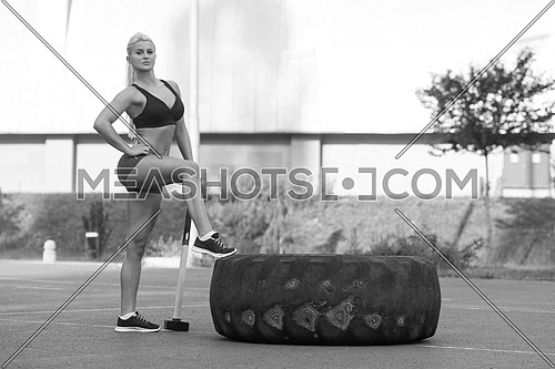 Portrait Of A Physically Fit Young Woman With Hammer And Tire Resting After Exercise