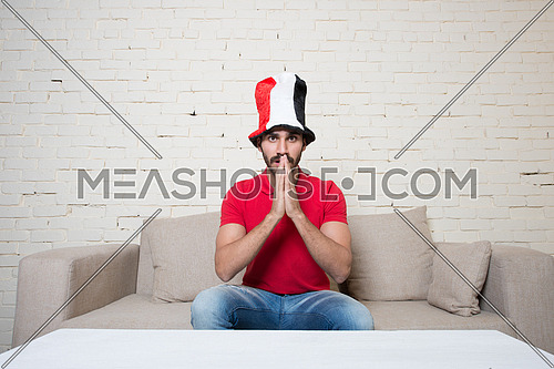 young man watching football game wearing Egyptian flag hat