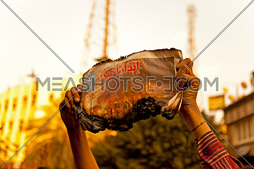 Man holding a burnt newspaper with title 